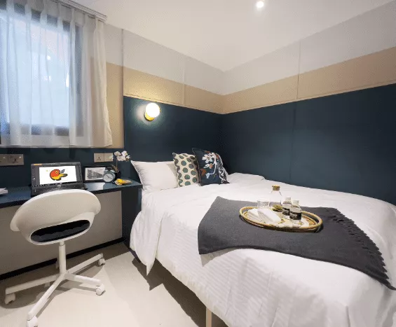 A Bilik hotel room at the ISA Hotel in Katong — a bed, a work desk, an en-suite bathroom and weekly housekeeping.