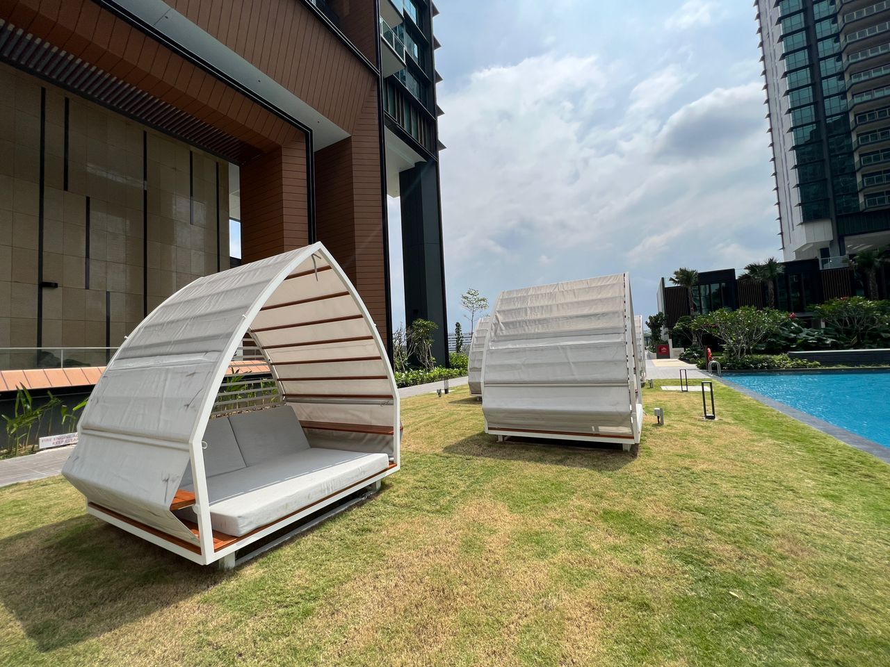 Shaded daybeds on the pool lawn — one of the quieter corners of the grounds.